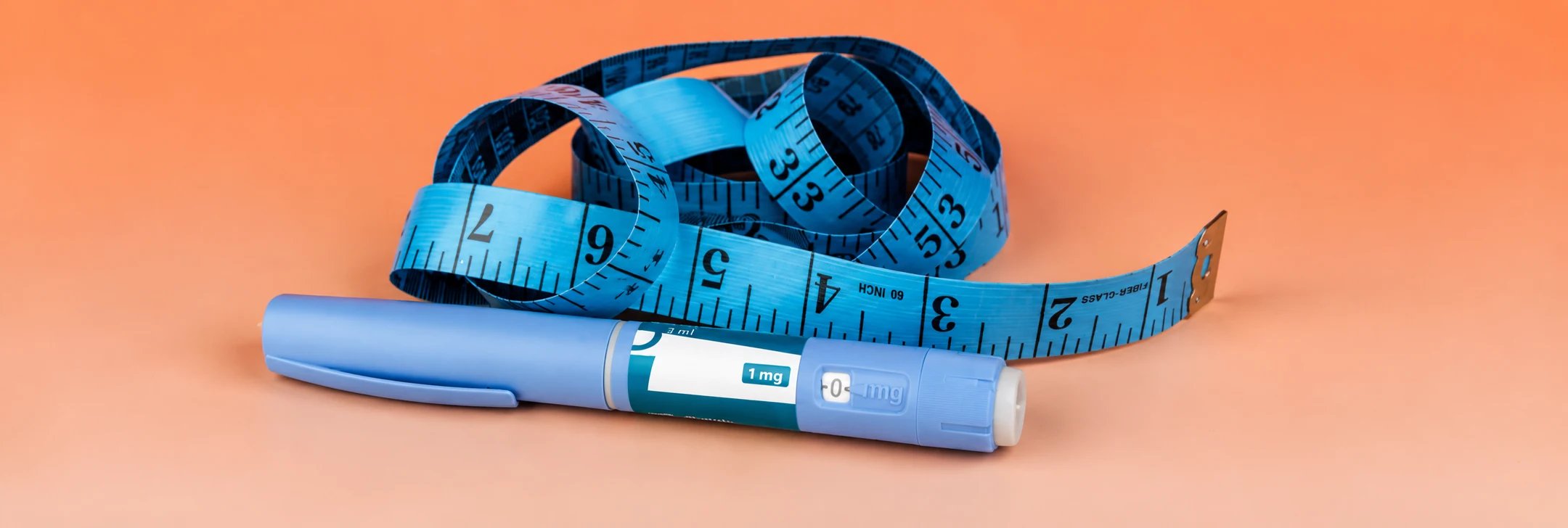 Maßband und Injektionsstift auf einem orangefarbenen Hintergrund