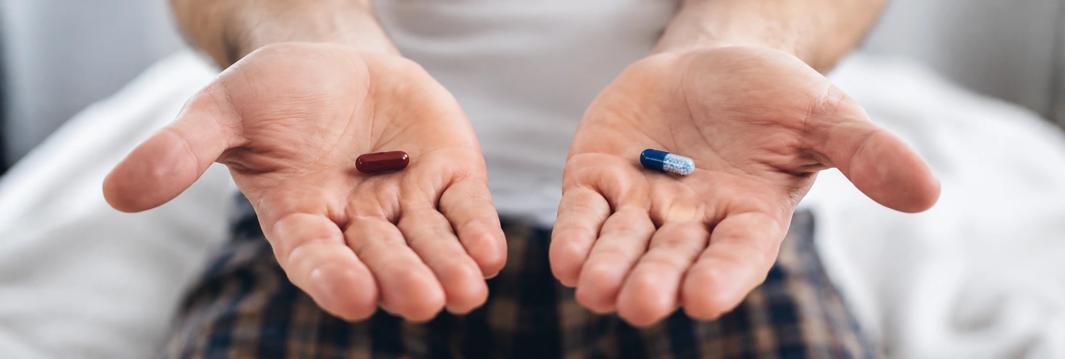 Man holding two different pills in each hand