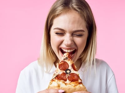 Eine Frau, die genüsslich Pizza isst