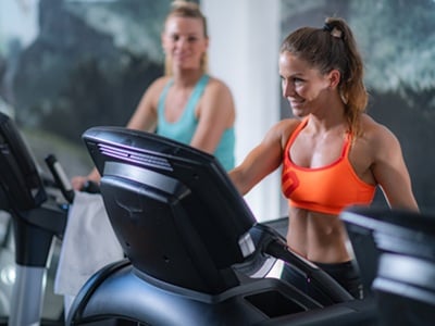 Aktive Frauen, die auf einem Laufband Herz-Kreislauf-Training betreiben