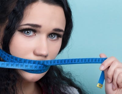 Eine junge Frau mit einem blauen Maßband über ihrem Mund