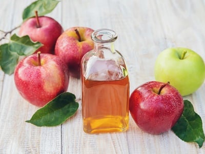 Eine Flasche Apfelessig mit frischen Äpfeln auf dem Tisch