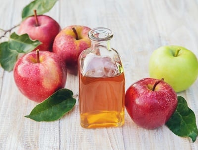 Apfelessig in einer Flasche und Äpfel