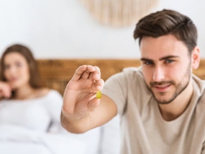 Ein l&auml;chelnder Mann, der vor dem Sex ein Cialis-Tablet in der Hand h&auml;lt.