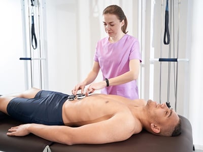 Ein Mann wird in einer Klinik mit Elektrostimulation behandelt