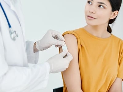 Eine medizinische Fachkraft legt einer ruhigen Frau nach der Verabreichung eines Corona-Impfstoffs vorsichtig einen Verband um die Schulter
