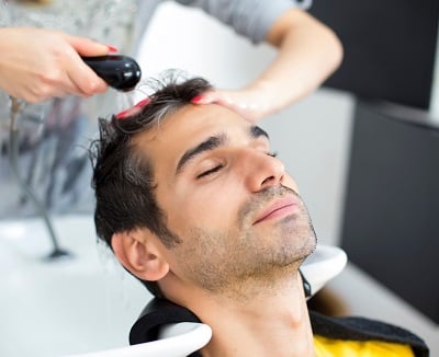 Ein Mann, der eine Haarpflege zur Vorbeugung von Geheimratsecken erhält