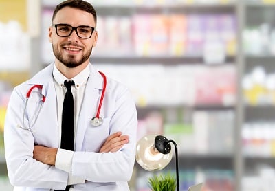 Arzt steht im Krankenhausb&uuml;ro und blickt in die Kamera