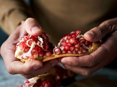 in Mann öffnet einen Granatapfel