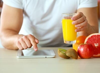 Ein Mann trinkt Grapefruit-Juice und liest auf dem Tablet