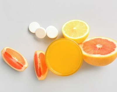 Grapefruits, ein Glas Zitrussaft und Tabletten