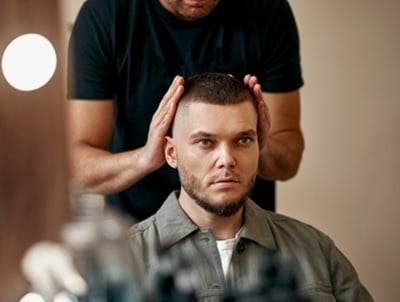 Ein Barbier und zufriedener Mann vor dem Spiegel