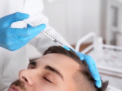 Ein junger Mann, der eine Injektionstherapie gegen Haarausfall erhält