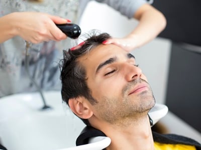 Ein Mann lässt sich professionell die Haare waschen