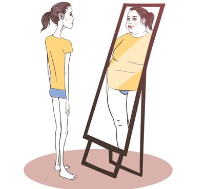 Junge Frau, die an Magersucht leidet, schaut in den Spiegel