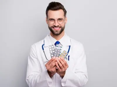 Médico sorridente segurando embalagens de comprimidos