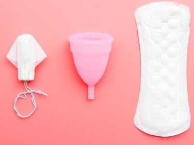 Eine Menstruationstasse, eine klassische Binde und ein Tampon