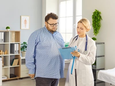 Ein &uuml;bergewichtiger Mann konsultiert eine &Auml;rztin bez&uuml;glich seines Abnehmprogramms