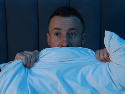  Ein Mann liegt nachts wach im Bett.