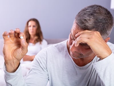 Ein Mann mit Erektionsproblemen hält eine Pille in der Hand