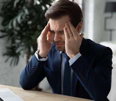 Ein Geschäftsmann, der aufgrund von Arbeitsstress unter Kopfschmerzen und Bluthochdruck leidet