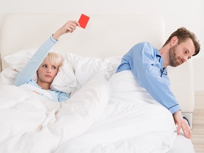 Unglückliche Frau zeigt dem Mann im Bett die rote Karte