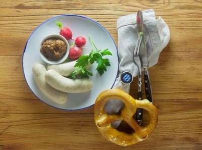 Traditionelle Oktoberfest-Speisen: Brezeln, Bier, Weißwurst und Schweinshaxe mit Senf