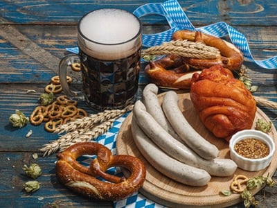 Traditionelle Oktoberfest-Speisen: Brezeln, Bier, Weißwurst und Schweinshaxe mit Senf