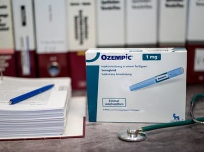 Eine Packung Ozempic neben einem Stethoskop und einem Stapel medizinischer Unterlagen