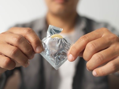 En man öppnar ett paket med kondom