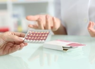 En farmaceut rådgiver en kvinde, der køber piller på et apotek
