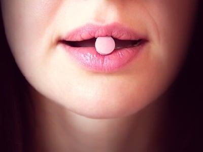 Eine pinke Tablette im Mund der Frau