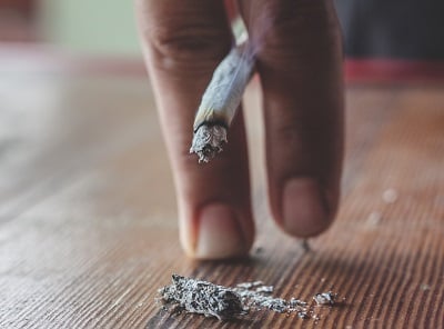 Eine verbrannte Zigarette zwischen zwei Fingern