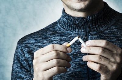 Ein Mann zerbricht eine Zigarette als Zeichen dafür, dass er mit dem Rauchen aufhört.