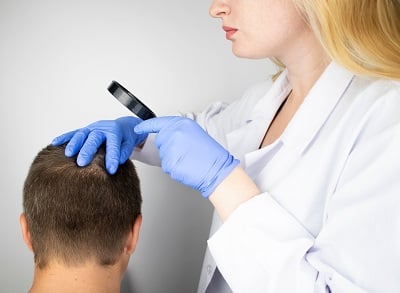 Ein Mann, der sich bei einem Trichologen wegen Haarausfall untersuchen lässt.