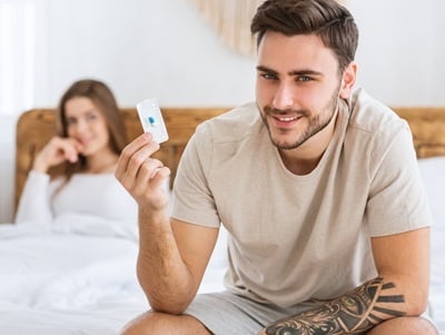 Ein l&auml;chelnder Mann, der vor dem Sex ein Tablet in der Hand h&auml;lt.