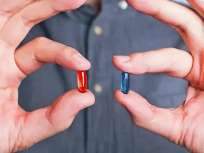 A man holding red and blue pills in his hands