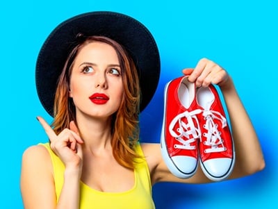 Eine schöne junge Frau, die Schuhe auswählt, um ihr Outfit zu vervollständigen