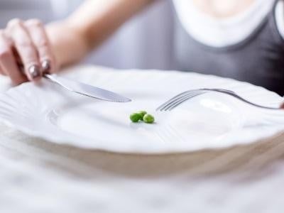 En ung kvinna som går på en extrem diet äter en mycket liten portion.