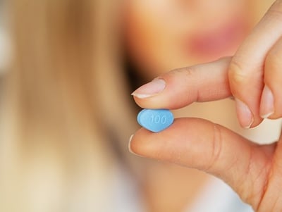 Eine Ärztin hält eine blaue Pille in der Hand
