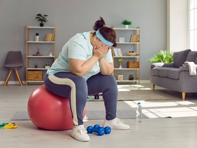 Eine frustrierte übergewichtige Frau, die auf einem Fitball sitzt