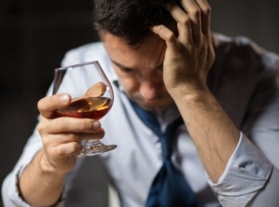 Ein betrunkener Mann mit einem Glas Alkohol