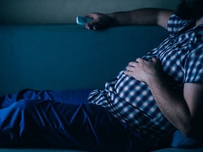 Ein Mann mit Bauch sieht fern, ohne sich zu bewegen