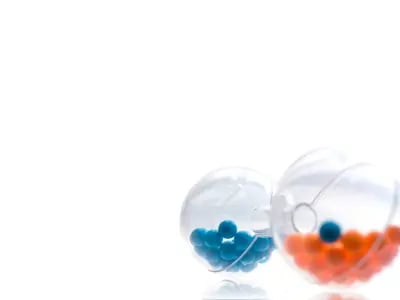 Blaue und orangefarbene Pillen aus transparenten Kapseln auf weißem Hintergrund