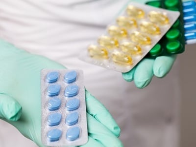 Eine &Auml;rztin, die in der einen Hand das Originalpr&auml;parat Viagra und in der anderen verschiedene Generika h&auml;lt.