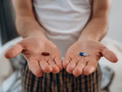 Man holding two different pills in each hand