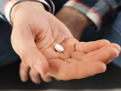 Ein Mann hält eine Tramadol-Tablette in seiner Handfläche
