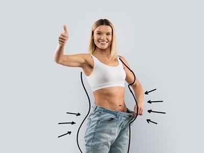 Eine Frau, die den Daumen hochhält, während sie die Ergebnisse ihrer Gewichtsabnahme vorführt.