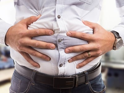Mann, der sich wegen Verstopfungsproblemen den aufgeblähten Bauch drückt