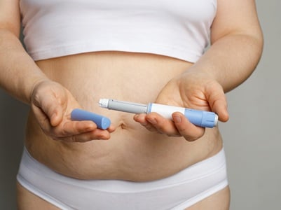 Eine Frau hält einen geöffneten Spritzen-Pen zum Abnehmen in der Hand.